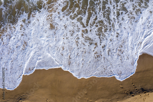 Aerial view of a remote sandy beach and sea waves