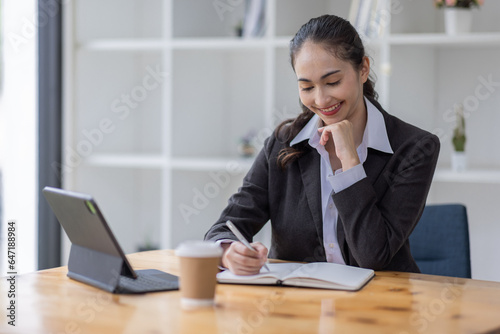 Young asian business woman having a coffee in an work on tablet the office