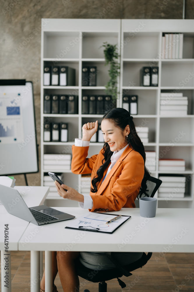 Asian business woman are delighted and happy with the work they do on their tablet, laptop and taking notes at the office.