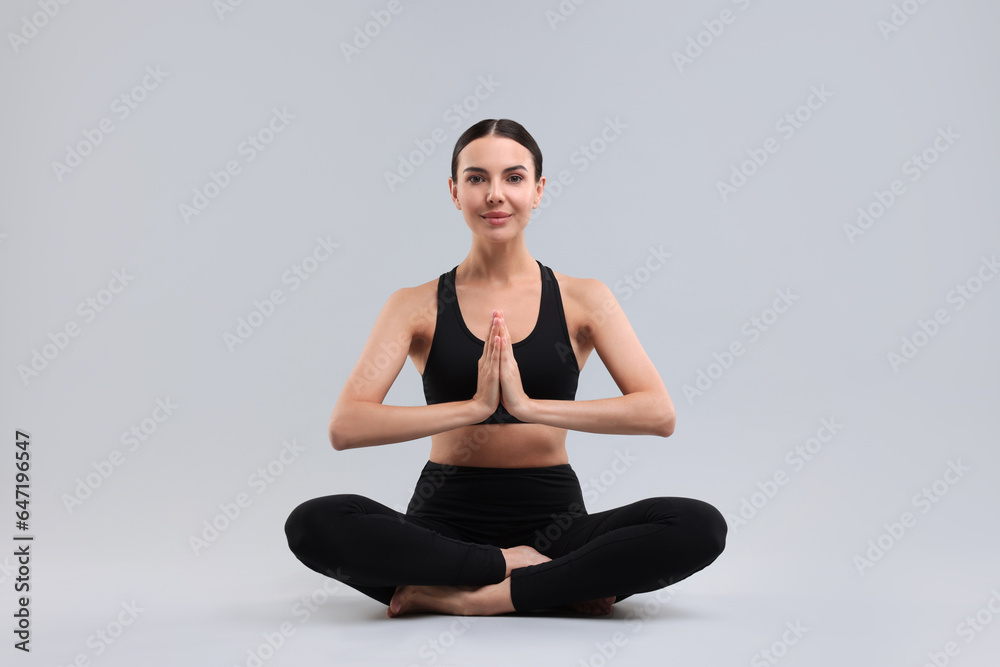 Beautiful young woman practicing yoga on grey background. Lotus pose Beautiful young woman practicing yoga on grey background. Lotus pose