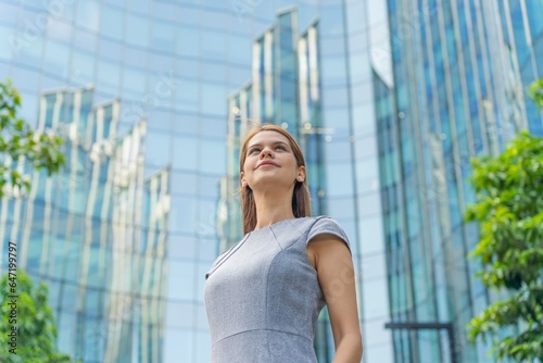 Portrait of a young and successful white caucasian business woman standing in front of a modern cityscape of office buildings