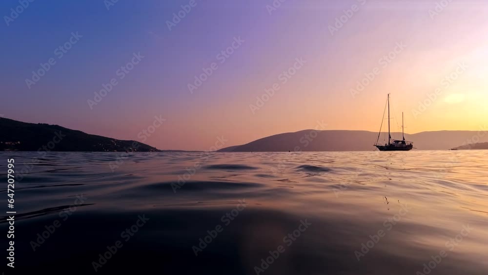 Yacht's silhouette against the backdrop of the sunset sky and mountains from the calm sea surface. Yacht's silhouette against the backdrop of the sunset sky and mountains from the calm sea surface.
