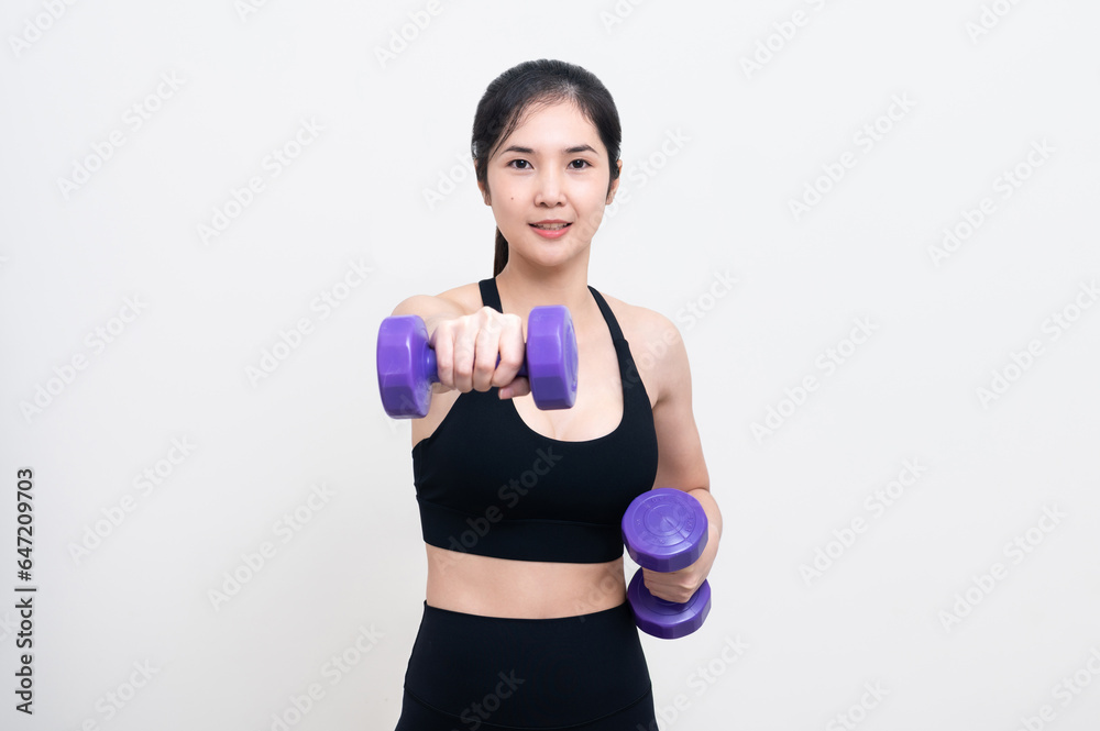 Asian woman wearing black workout clothes with smiling face Exercising with purple dumbbells with cheerfulness against a white background or isolated Asian woman wearing black workout clothes with smiling face Exercising with purple dumbbells with cheerfulness against a white background or isolated