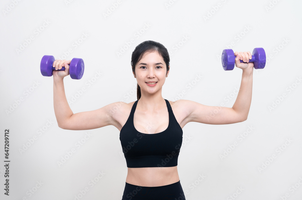 Asian woman wearing black workout clothes with smiling face Exercising with purple dumbbells with cheerfulness against a white background or isolated Asian woman wearing black workout clothes with smiling face Exercising with purple dumbbells with cheerfulness against a white background or isolated