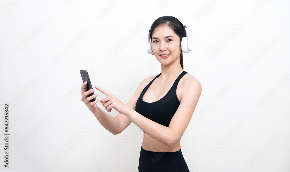 Happy slim asian woman in black workout clothes listening to music through headphones Holding phone and social media while exercising isolated with white background Happy slim asian woman in black workout clothes listening to music through headphones Holding phone and social media while exercising isolated with white background