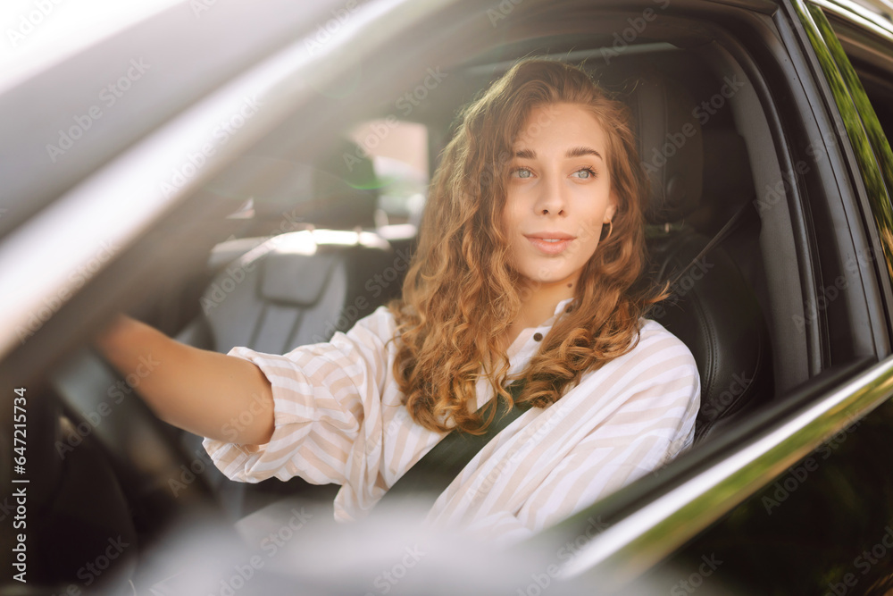 Cute woman in casual clothes is sitting behind the wheel of a car. Traveler-driver. Concept of mode of transportation, travel. Cute woman in casual clothes is sitting behind the wheel of a car. Traveler-driver. Concept of mode of transportation, travel.