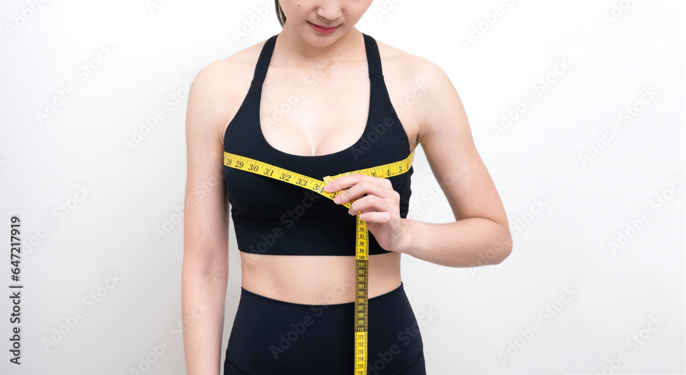 Slim Asian woman in black workout clothes Measure her waist with a yellow tape measure. She doesn't know her waist size. and checking waist size Isolated on white studio wall Slim Asian woman in black workout clothes Measure her waist with a yellow tape measure. She doesn't know her waist size. and checking waist size Isolated on white studio wall