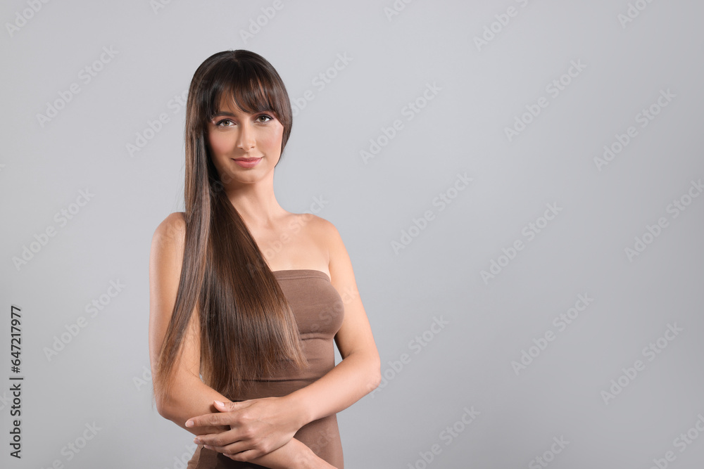 Hair styling. Portrait of beautiful woman with straight long hair on grey background, space for text Hair styling. Portrait of beautiful woman with straight long hair on grey background, space for text