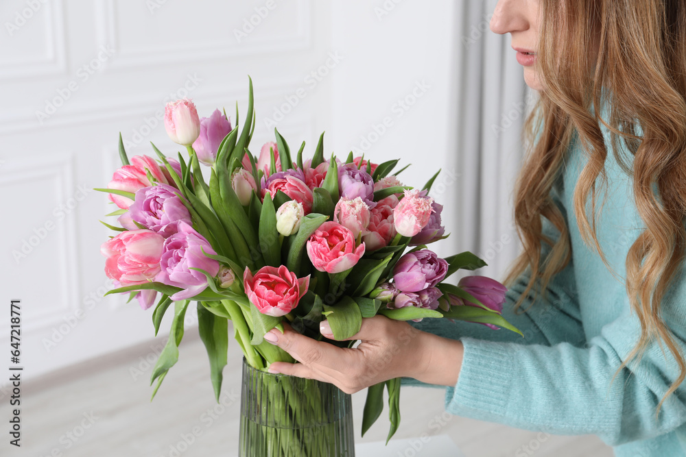 Woman putting bouquet of beautiful tulips in vase indoors, closeup Woman putting bouquet of beautiful tulips in vase indoors, closeup