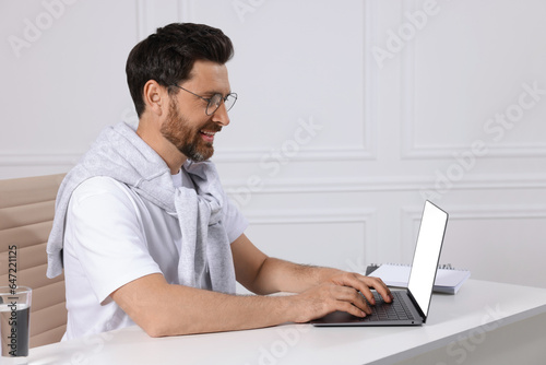 Man using laptop at white table indoors