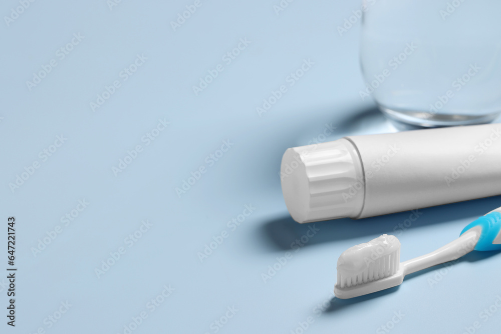 Plastic toothbrush with paste and glass of water on light background, space for text Plastic toothbrush with paste and glass of water on light background, space for text