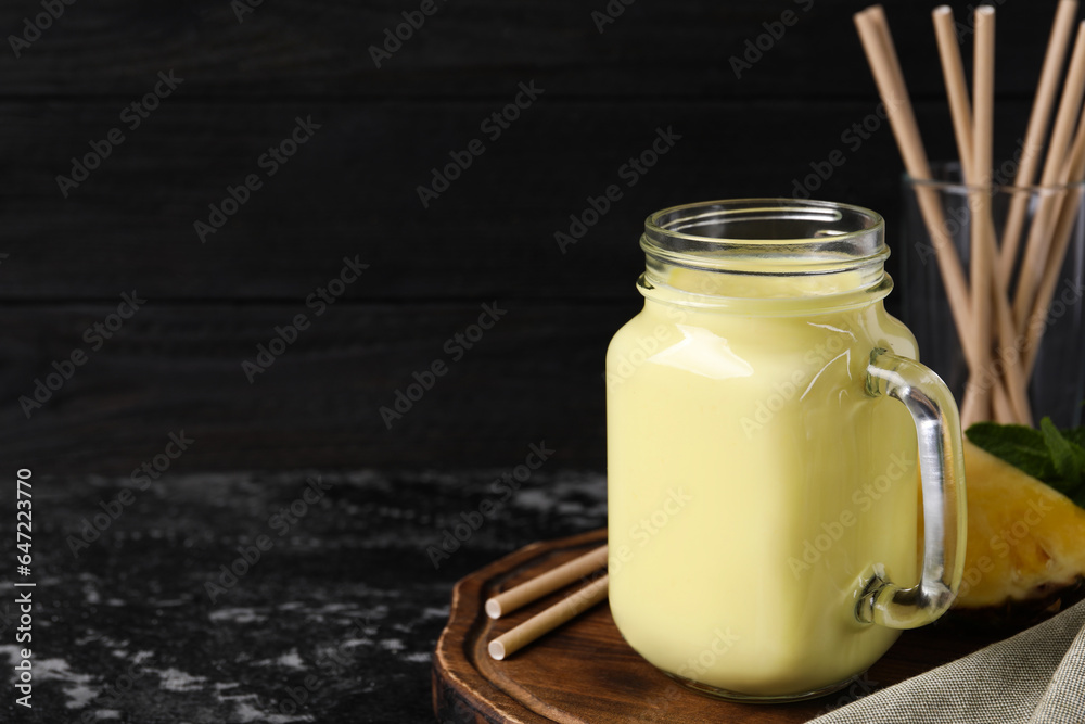 Tasty pineapple smoothie, slice of fruit and straws on dark textured table. Space for text Tasty pineapple smoothie, slice of fruit and straws on dark textured table. Space for text
