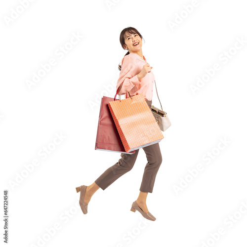 ショッピングバッグを持ってジャンプするミドル女性