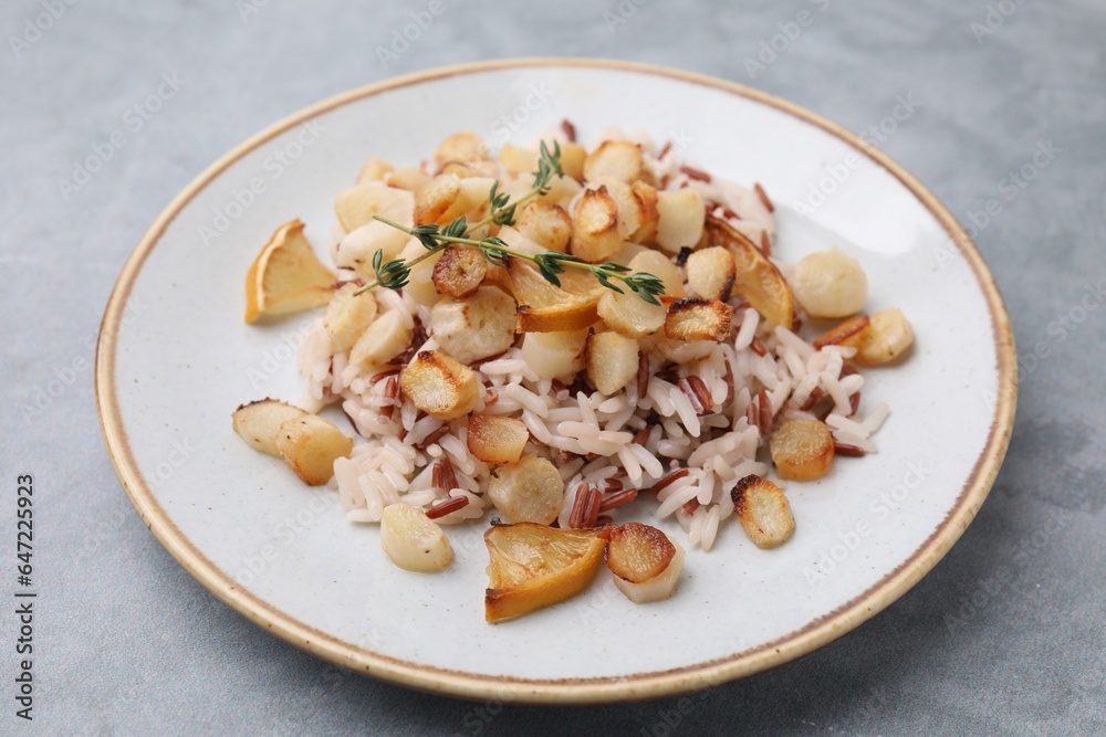 Plate with baked salsify roots, lemon and rice on light grey table, closeup Plate with baked salsify roots, lemon and rice on light grey table, closeup