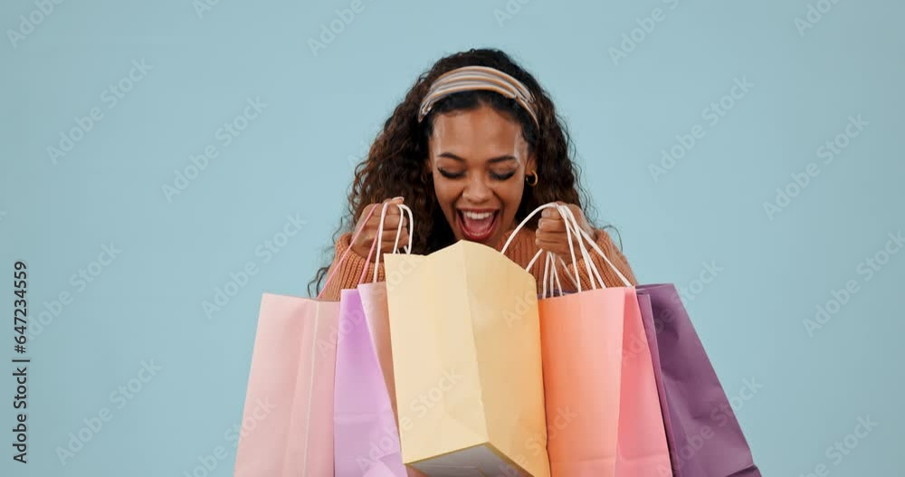 Face, excited and woman with bags, shopping and client with fashion on a blue studio background. Portrait, person and client with excitement, expensive clothes and luxury items with wow and retail Face, excited and woman with bags, shopping and client with fashion on a blue studio background. Portrait, person and client with excitement, expensive clothes and luxury items with wow and retail
