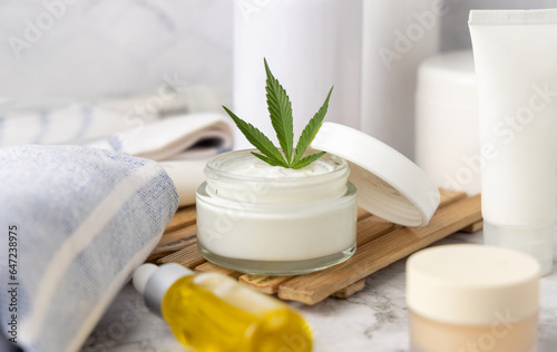 Opened cream jar with green cannabis leaves close up, organic natural CBD cosmetic
