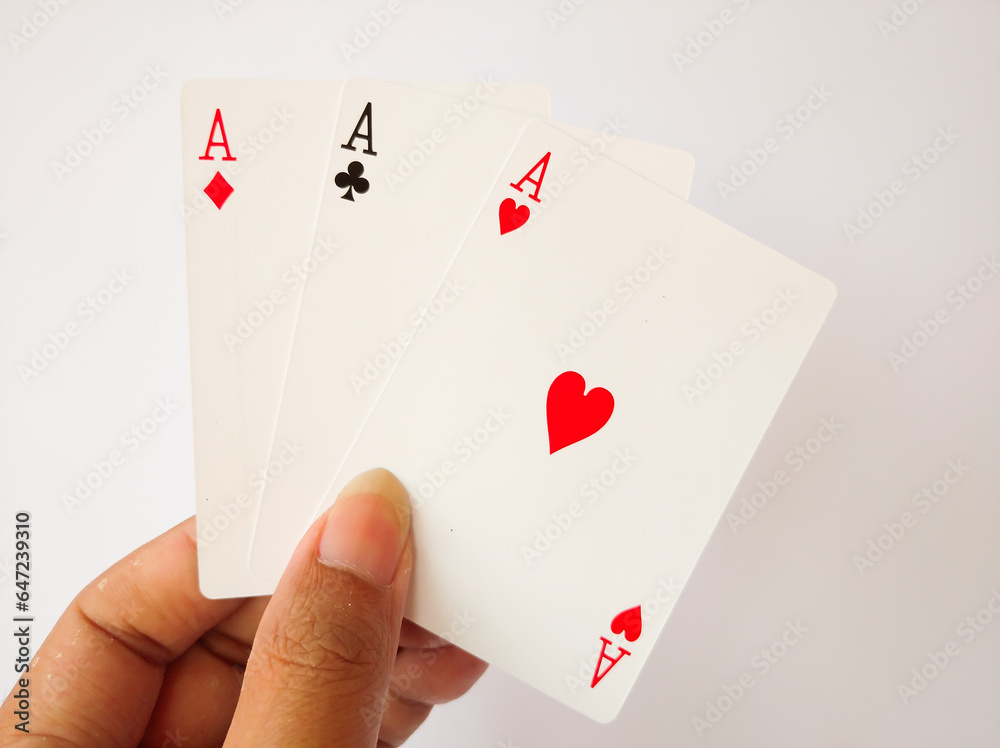 The person holds three playing cards the ace of hearts, diamonds and clubs