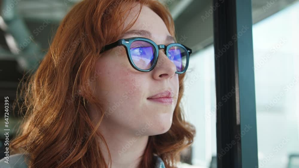 Business woman standing in an office and looking outside a window. Female professional looking away thoughtfully. Business woman standing in an office and looking outside a window. Female professional looking away thoughtfully.
