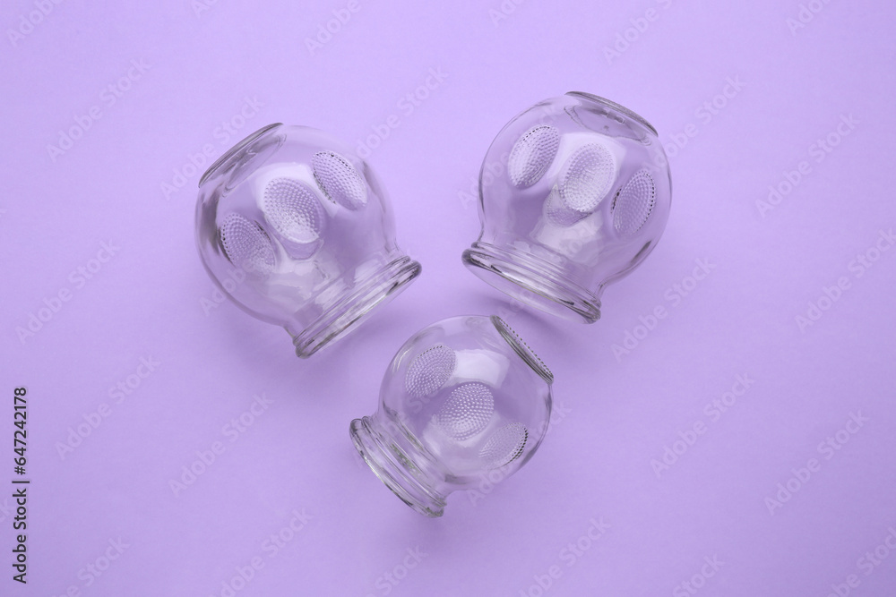 Glass cups on violet background, flat lay. Cupping therapy Glass cups on violet background, flat lay. Cupping therapy