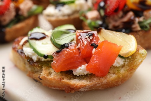Delicious bruschetta with balsamic vinegar and toppings on white board, closeup