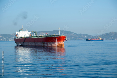 Container cargo ship loaded leaves Piraeus port, Greece. Smoke from ship chimney, sea, blue sky.