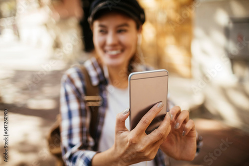 Happy young Asian woman using a smartphone while walking in the city