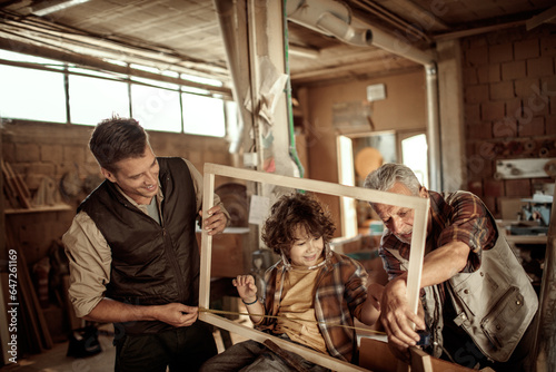 Multigenerational family including a son , father and grandfather working with wood in a carpentry workshop
