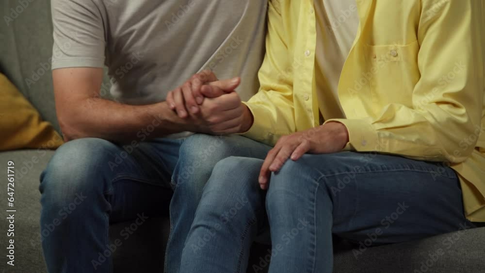 Close up video of a homosexual couple at home. The men are sitting on the couch, holding hands and expressing love to each other warmly. Close up video of a homosexual couple at home. The men are sitting on the couch, holding hands and expressing love to each other warmly.