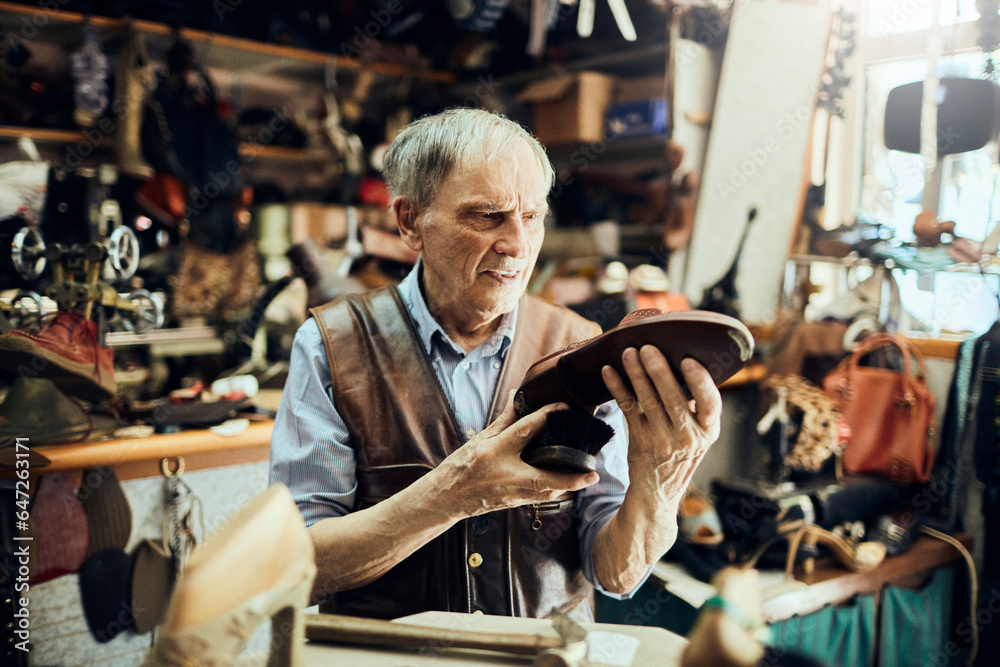 Senior male shoemaker restoring a shoe in his old workshop in the city Senior male shoemaker restoring a shoe in his old workshop in the city