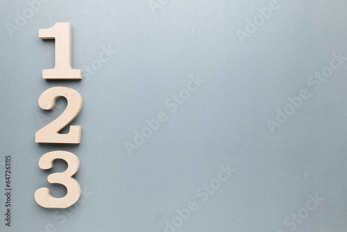 One, Two, Three, wooden numbers on gray paper with copy space photo