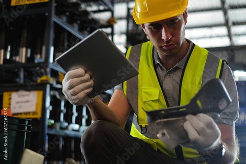 Caucasian male engineer holding tablet with car spare parts to check quality of workpieces in automobile factory.