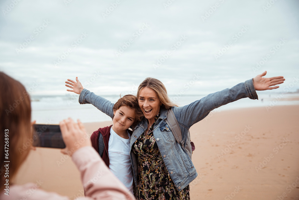 Young family taking pictures of each other while on vacation on a beach
