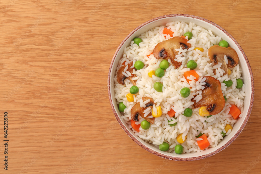 Bowl of delicious rice with vegetables on wooden table, top view. Space for text Bowl of delicious rice with vegetables on wooden table, top view. Space for text