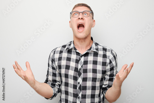 Portrait of angry young man screaming holding hands in furious gesture isolated on white studio background. Devil boss face. Human emotions, facial expression concept