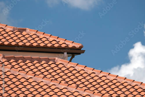 Overlapping rows of yellow ceramic roofing tiles covering residential building roof in southern Florida