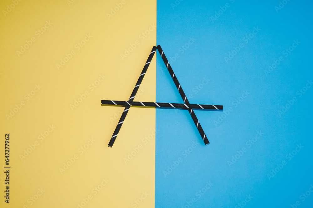 Letter A made from black straws on a colorful background. Flat lay.