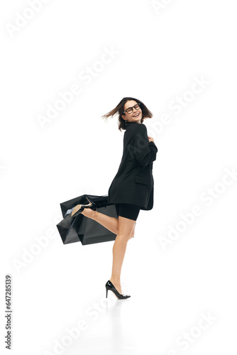 Black friday concept. Full lenth portrait of young woman wearing fashion office outfit enjoying shopping, purchases with huge bags. Shopaholik