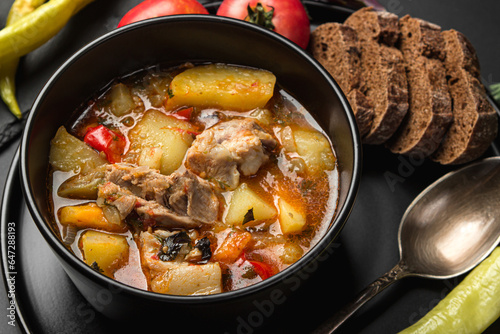 Stewed meat and vegetables in a black plate on a dark background