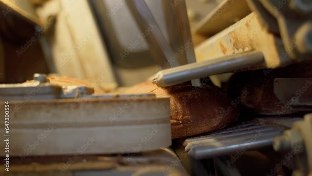 Bread cutting mechanism on a conveyor line in a factory indoors. Close-up Bread cutting mechanism on a conveyor line in a factory indoors. Close-up