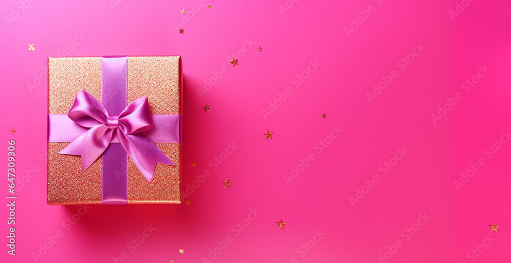 Top view of gold box with pink ribbon on a magenta pink background with gold confetti. Christmas background with copy space. Top view of gold box with pink ribbon on a magenta pink background with gold confetti. Christmas background with copy space.