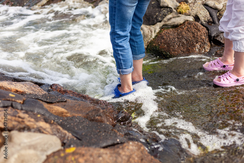 Woman's legs in slippers on the rocks near the sea.
