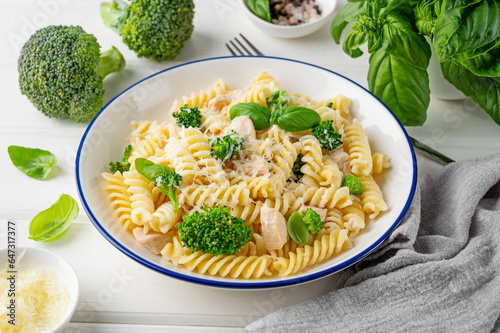 фотографія Delicious broccoli and chicken fusilli pasta with parmesan cheese and fresh basil in a bowl on a white wooden background