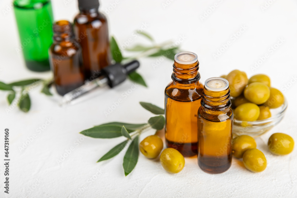 Olive essential oil. Glass bottle with olive oil on a texture table. Olive cosmetic oil. Serum for moisturizing and nourishing skin and hair. Beauty concept. Natural cosmetic. Copy space.spa Olive essential oil. Glass bottle with olive oil on a texture table. Olive cosmetic oil. Serum for moisturizing and nourishing skin and hair. Beauty concept. Natural cosmetic. Copy space.spa