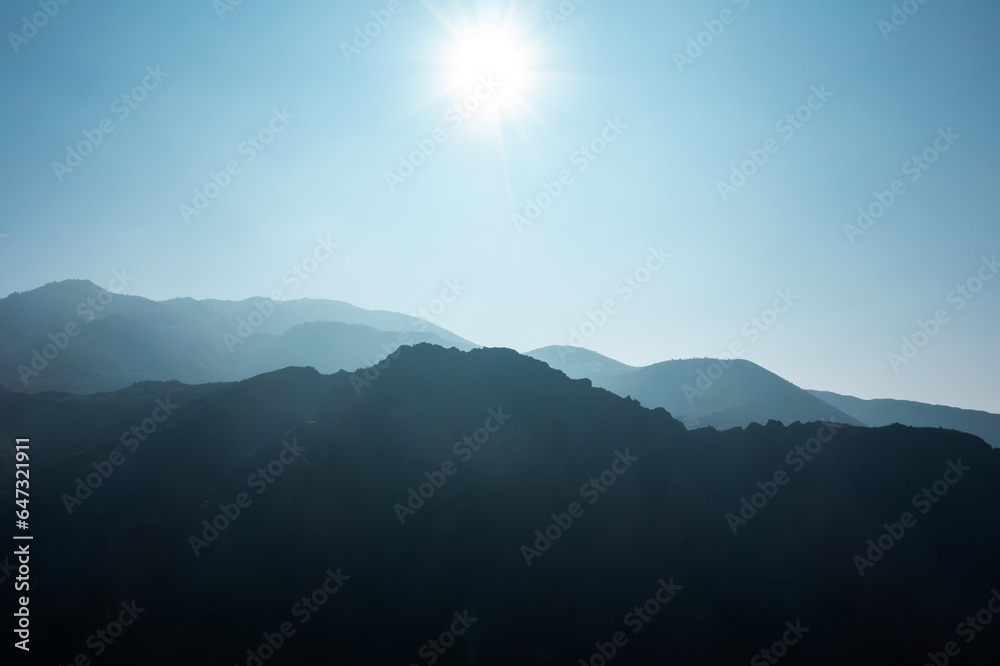 Layers of blue mountain silhouette with sunny blue sky