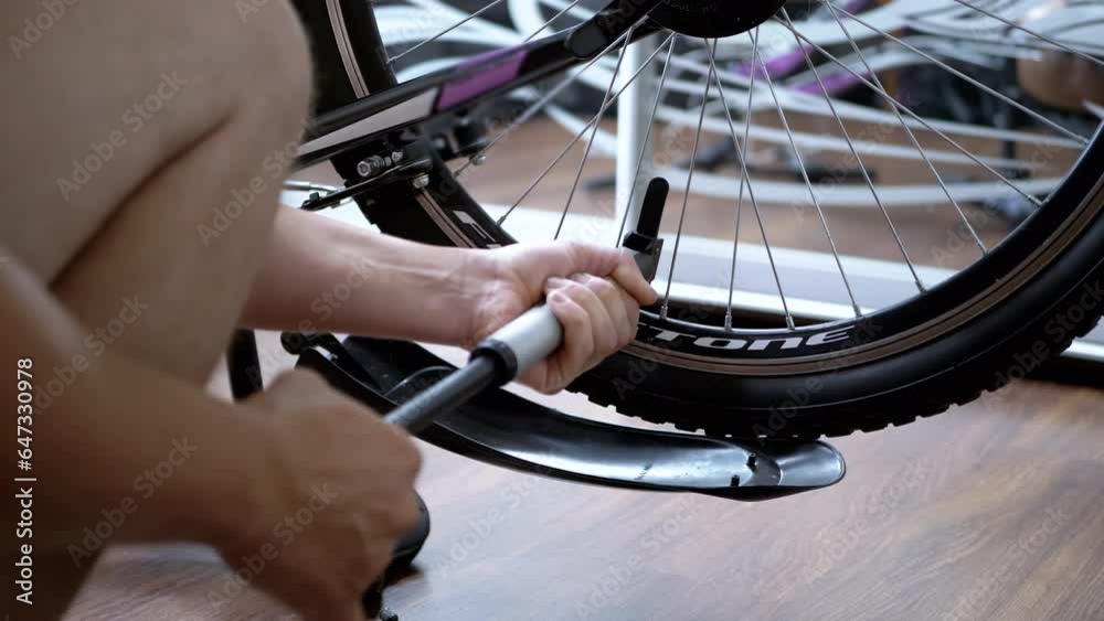 Close up, Male Hands Pumps Air into a Flat Tire on a Bicycle using a