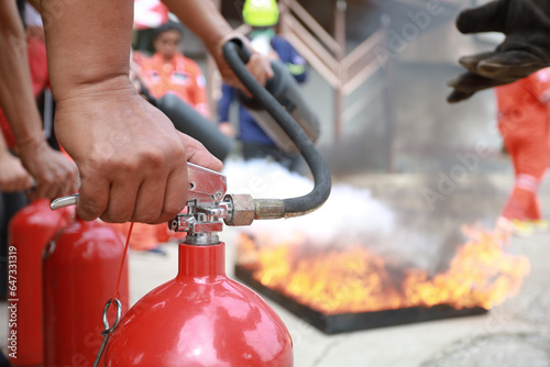 Employees firefighting training, Concept Employees hand using fire extinguisher fighting fire closeup