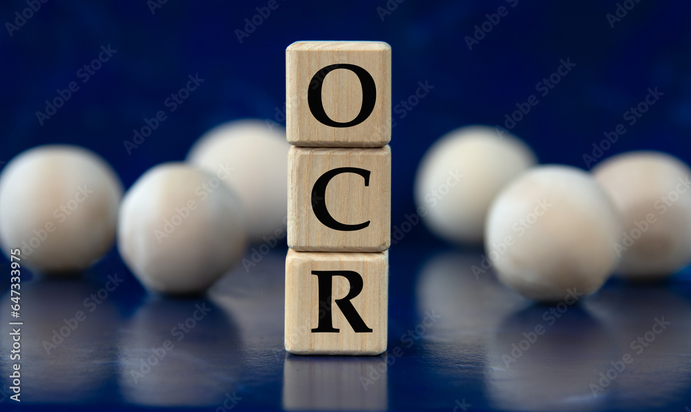 OCR - acronym on wooden cubes on a blue background with wooden balls OCR - acronym on wooden cubes on a blue background with wooden balls