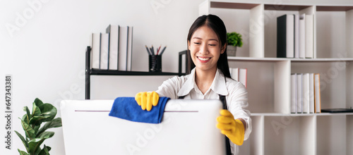 Housewife in apron wearing gloves to using microfiber fabric to wiping cleanup computer and furniture