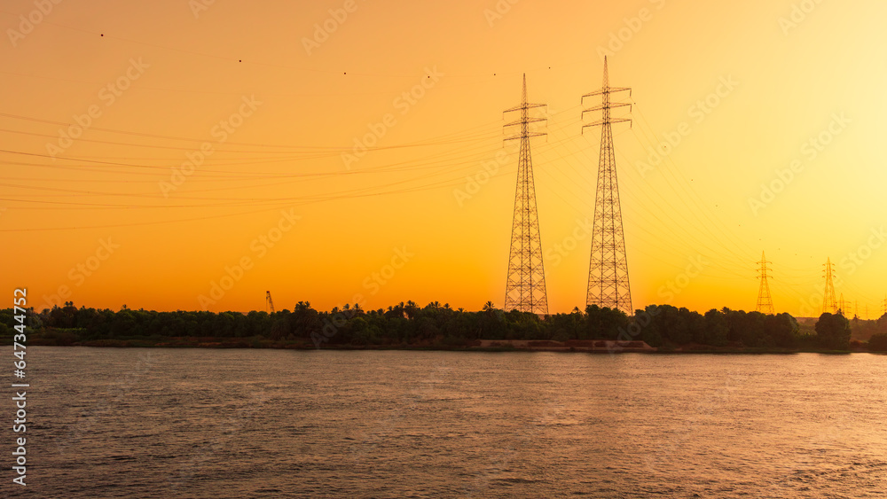 Power lines on bank of the River Nile at sunset