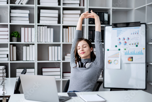 Businesswoman with technology lifestyle concept, Businesswoman wearing headphone in her neck and holding hands behind the head to stretching with close eyes while relaxation after working